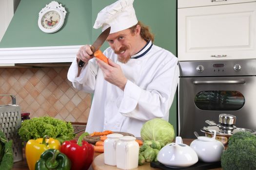 Funny young chef with carrot, preparing lunch in kitchen