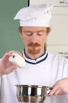 Young chef add salt in the pot, preparing lunch 