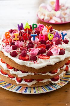 Delicious cake with candy letters on top that read happy birthday