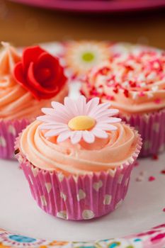 Bright colored birthday cupcake decorated with flower made of sugar