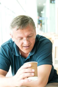 Middle age man in glasses looking into coffee cup
