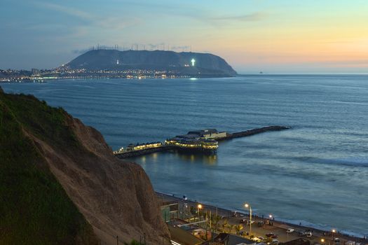 The coastline of Lima, Peru at twilight with the Restaurant La Rosa Nautica reaching into the sea on a pier