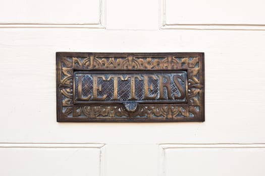 Ornate letterbox in a white wooden door