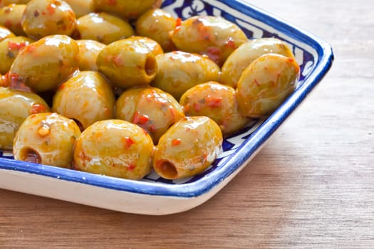 A dish of green olives with red chilli pepper