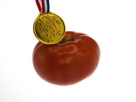 tomato with a gold medal winner pendant on a wooden background