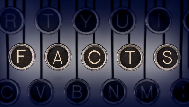 Image of old typewriter keyboard with scratched chrome keys that spell out the word "FACTS". Lighting and focus are centered on "FACTS".