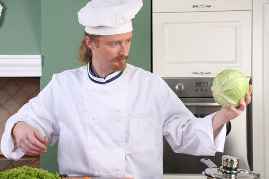 Young chef with cabbage, preparing lunch in kitchen 