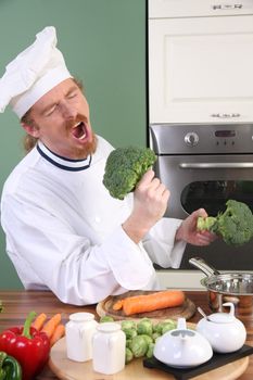 Funny young Chef with broccoli, preparing lunch in kitchen