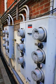 Several rows and boxes of power meters on the red brick wall of an apartment