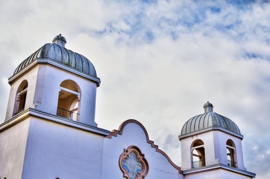 HDR image of a spainsh mission style stucco church with partly cloudy sky