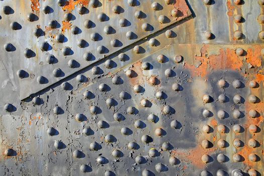 Old rusty rivets on large corroding steel plates of a train and auto Bridge