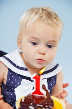 A little sweet girl with a cake and a candle in her first birthday.