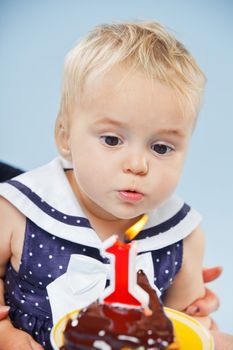 A little sweet girl with a cake and a candle in her first birthday.