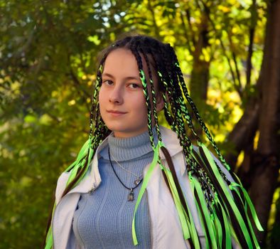 girl with pigtails with a Mona Lisa smile against the backdrop of autumn forest