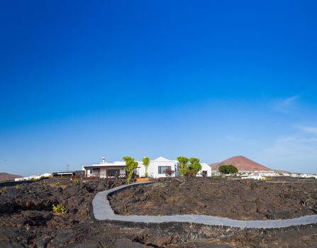 Panorama of a typical cottage with road, built on the lava of the volcano. Lanzarote, Canary Islands