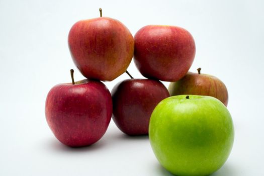 A tower of red apples with a single green apple in front