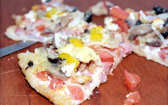 Parts of cutting pizza with ham, mushroom, tomatoes, paprika and cheese