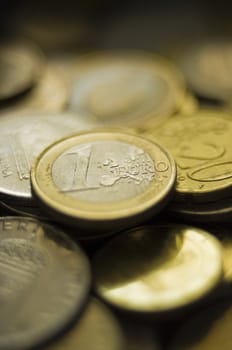 One euro coin at the top of blurred coins stack