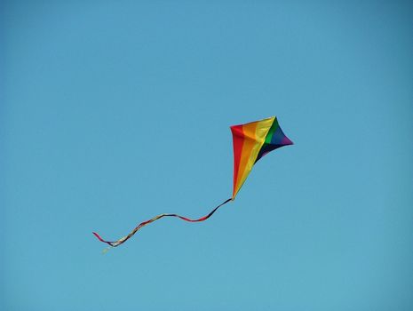 Bright coloured kite flying on a clear day with a blue sky