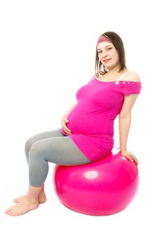 happy beautiful pregnant woman making some exercises on a fitness ball