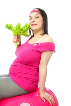 beautiful pregnant woman sitting on the fitness ball and eating green salad