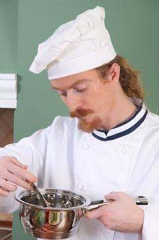 young Chef tasting food with a tablespoon 