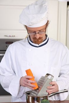 Young chef with carrot, preparing lunch in kitchen