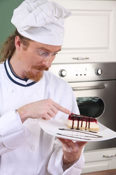 Funny young chef strange looking at piece of cake with chocolate sauce