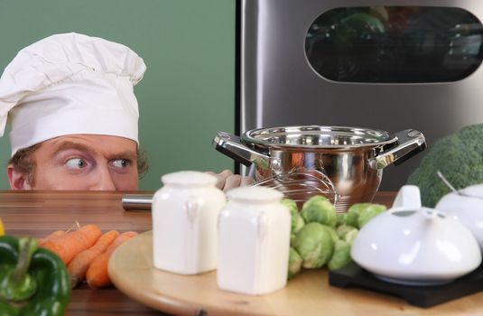 Funny young chef strange looking at pot