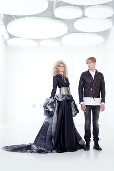 Black haute couture retro futurist couple in modern white hall with vampire inspiration