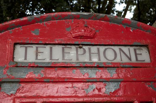 Photograph of a small portion of traditional red British Telephone Box in a bad state of repair.