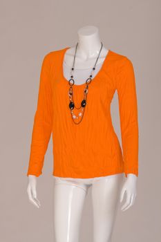 Mannequin dressed in a orange shirt and fashionable chain