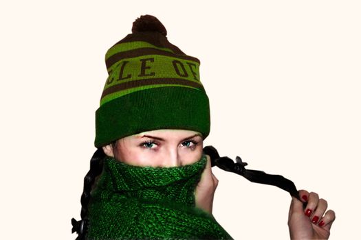 Young woman with green eyes in hat and a sweater covers part of the face
