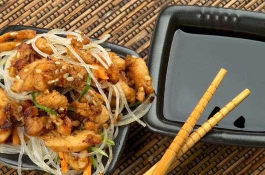 Chicken Teriyaki. Chinese Glass Noodles and Soy Sauce in Black Square Shape Bowls with Pair of Chopsticks on Straw mat background