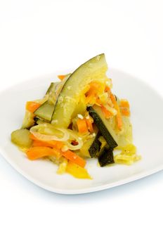 Zucchini Ragout with Carrot, Leek and Bell Pepper on Square White Plate isolated on white background