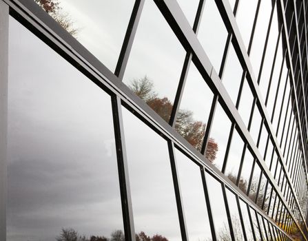 Angled glass wall bent inward reflecting trees and sky