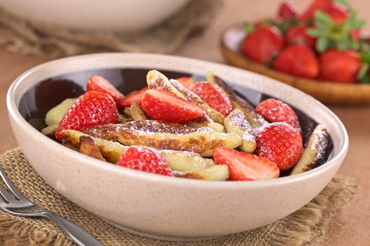 Schupfnudeln (Swabian potato noodles from Southern Germany) with fresh strawberries, cinnamon and sugar powder (Selective Focus, Focus on the front of the three strawberry pieces in the middle of the bowl) 