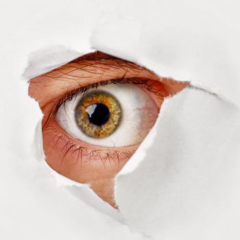 The eye looks through a hole in the paper - a spy