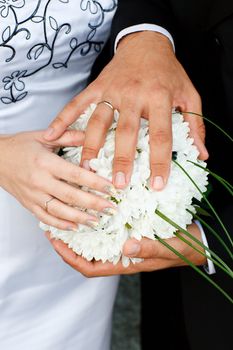 hands of bride and groom on the bouquet