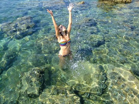 Young woman in bikini splashing for fun
