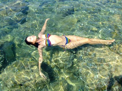 Young woman in bikini floating in clear shallow water