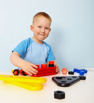 A little boy sitting at a table. Playing