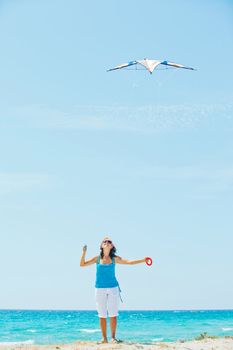 Young cute woman playing with a colorful kite on the tropical beach. Vertikal veiw