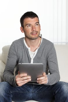 handsome man on sofa with tablet looking someone