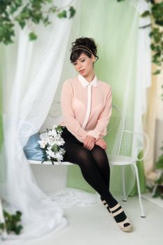 A woman in a pink blouse sitting on a bench in the green.