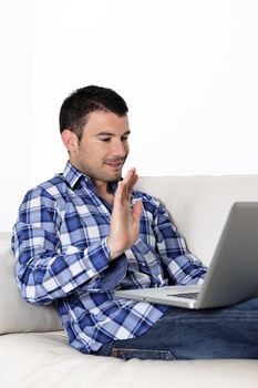 Portrait of a man waving at a laptop