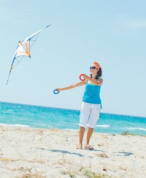 Young cute woman playing with a colorful kite on the tropical beach. Vertikal veiw