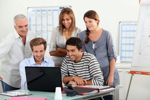 Co-workers gathered around computer screen