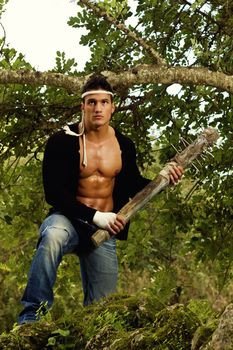 View of a fighter male holding a mace weapon on a forest.