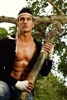 View of a fighter male holding a mace weapon on a forest.